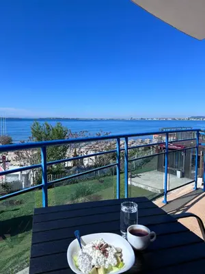 a table with a plate of food and a view of the beach at Vega Stevi Vlas - Beachfront in Sveti Vlas
