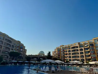 a swimming pool with chairs and umbrellas and buildings at Black Sea Residence Aheloy in Aheloy