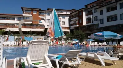 a group of chairs and umbrellas in a swimming pool at Gardenia Hills in Sunny Beach
