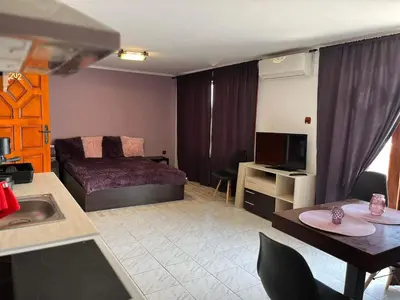 a living room with a bed and a kitchen with a table at Villa Nikoleta in Sveti Vlas