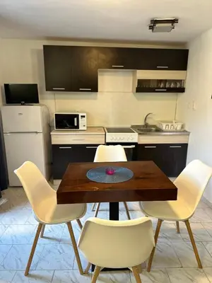 a kitchen with a wooden table and white chairs at Vila Nikoleta in Sveti Vlas