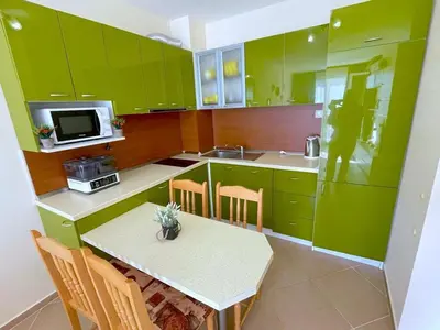 a kitchen with green cabinets and a table with chairs at Sun and Sea A22 in Sunny Beach
