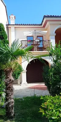 a house with a garage with a balcony and a palm tree at Apartment 300m from private beach VILA ROMANA Royal Castle in Sveti Vlas