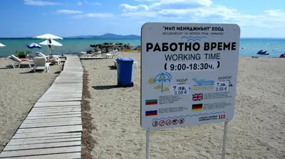 a sign on the beach next to a wooden pier at Gnezdo Apartment Sarafovo in Burgas City