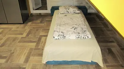 a bed in a room with a wooden floor at Gnezdo Apartment Sarafovo in Burgas City