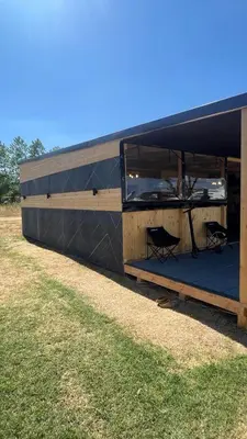 a building with a black roof on a grass field at Бунгало woodwave in Chernomorets