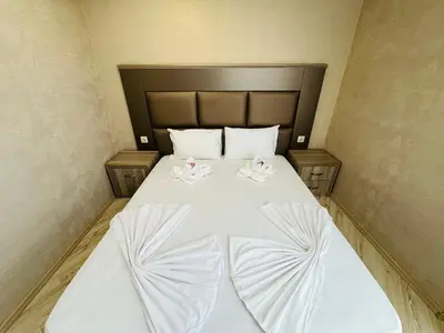 a bed with white sheets and pink flowers on it at PARADISO B 411 Large SEA VIEW Studio Nessebar in Nesebar