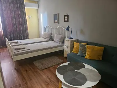 a room with two beds and a couch and a table at Стая за двама в град Бургас in Burgas City