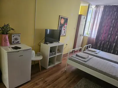 a small room with a bed and a tv at Стая за двама в град Бургас in Burgas City