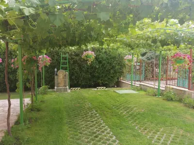 a garden with a ladder and a fence with pink flowers at Affordable Rooms with BBQ 5 min drive from beach Villa Lusi in Varna City
