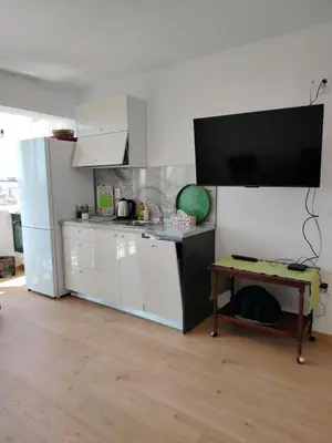 a kitchen with white cabinets and a table and a television at Level 5 in Burgas City