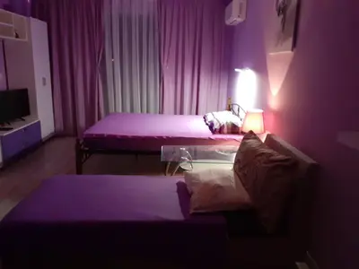 a purple room with two beds and a table at Parus 4 Studio in Pomorie