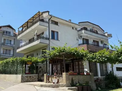 a large white building with a person sitting in front of it at Guest House Bа́kish Obzor in Obzor