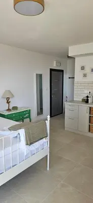 a white bedroom with a bed and a kitchen at Cozy sea view studios in Sozopol