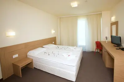 a hotel room with a large bed and a desk at Jeravi Club Hotel - All Inclusive in Primorsko
