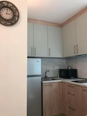 a kitchen with a white refrigerator and a clock on the wall at Първа Линия Лазур Поморие in Pomorie