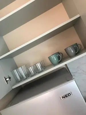 a kitchen shelf with cups and plates on it at Първа Линия Лазур Поморие in Pomorie