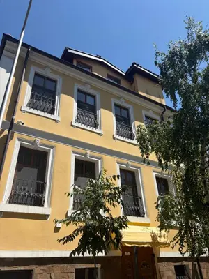a yellow building with white windows and a tree at Hogo Fogo in Burgas City