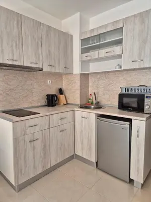 a kitchen with wooden cabinets and a microwave at Комфортен Апартамент Лазур in Pomorie
