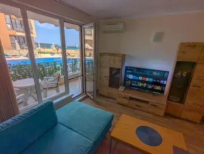 a living room with a couch and a tv and a balcony at Obzor Beach Resort F001 Urlaub BG in Obzor