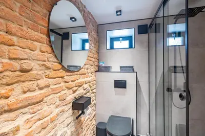 a bathroom with a brick wall and a mirror at Skyler 9 in Varna City
