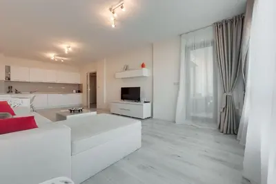 a living room with a white couch and a kitchen at АТ apartment - South Bay Beach Residence in Varna City