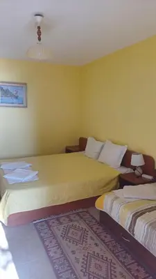 two beds in a room with yellow walls and a rug at Rooms Ivanka Ground Floor in Obzor