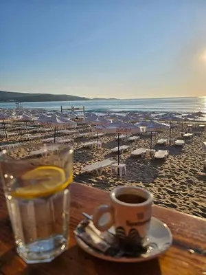 a table with a glass of water and a cup of coffee at Family Hotel California in Primorsko