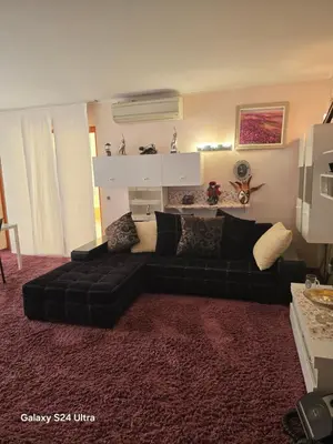a living room with a black couch and a red rug at Несебър Златна Дюна in Nesebar