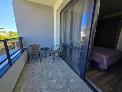a room with a balcony with a bed and chairs at villa Amethyst, private pool with heating and salt water in Lozenets