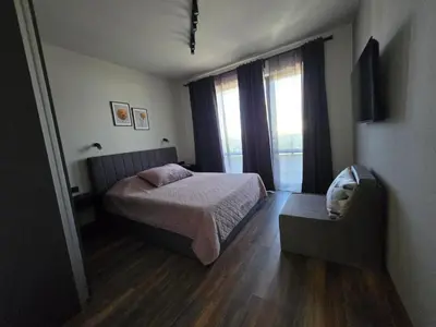 a bedroom with a bed and a chair and a window at villa Amethyst, private pool with heating and salt water in Lozenets