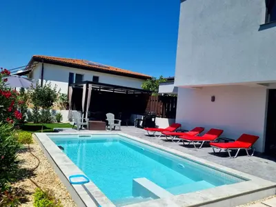 a swimming pool with red chairs next to a house at villa Amethyst, private pool with heating and salt water in Lozenets