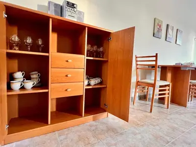 a wooden cabinet with a chair in a room at Velika Garden Villas 1 bedroom apartment, Lozenets in Lozenets