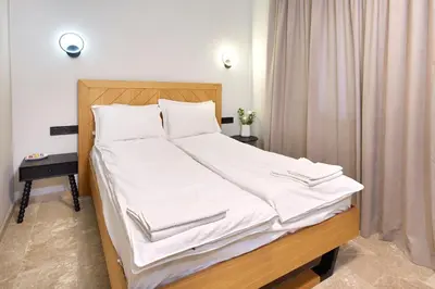 a large bed with white sheets and pillows at Семеен хотел НОА in Nesebar