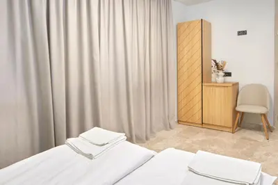 a room with two beds and a cabinet and curtains at Семеен хотел НОА in Nesebar
