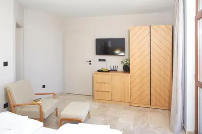 a living room with a tv and a wooden cabinet at Семеен хотел НОА in Nesebar