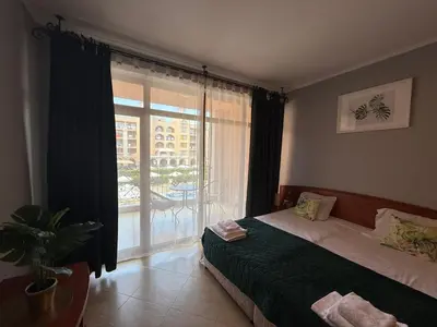 a bedroom with a bed and a window with a balcony at Palazzo SP apartments-Sunny Beach in Burgas City