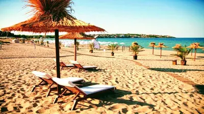 a beach with chairs and a straw umbrella and the ocean at Romantic Studio Florence in Sveti Vlas