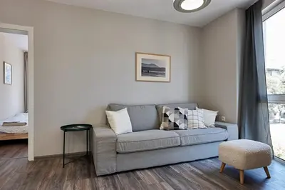 a living room with a gray couch and a window at Green Corner Apartment in the Center - 2BD in Burgas City