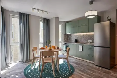a kitchen with a table with chairs and a refrigerator at Green Corner Apartment in the Center - 2BD in Burgas City