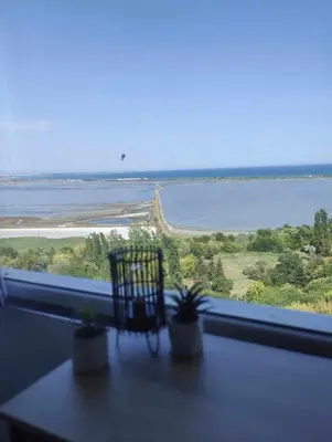 a window with a chair and a view of the water at Sky Sea Apartment in Burgas City