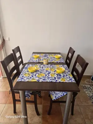 a dining room table with a table cloth with yellow dishes on it at Апартамент Хелиос Поморие in Pomorie