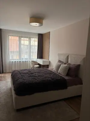 a bedroom with a bed and a desk and a window at Дизайнерски апартамент in Burgas City