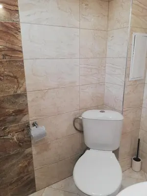 a bathroom with a white toilet and a tiled wall at Relax in Tsarevo