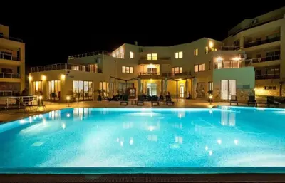 a large swimming pool in front of a building at night at The white flat in Byala