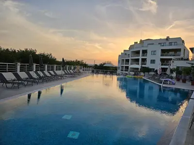 a large swimming pool with chairs and a building at The white flat in Byala