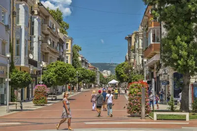 a group of people walking down a city street at ap Knyaz Boris I in Varna City