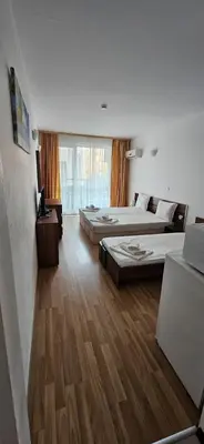 two beds in a room with wooden floors at Библиотеката in Pomorie