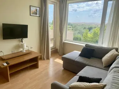 a living room with a couch and a large window at Peaceful, Top Floor, 2 Bedroom in Sunny Beach