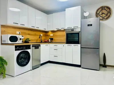 a kitchen with white cabinets and a washer and dryer at Sea Breeze in Burgas City